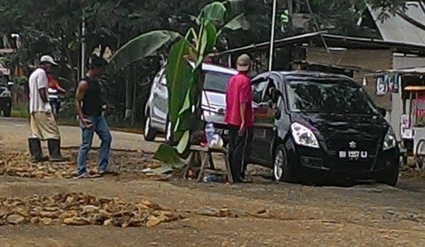 Warga yang memperbaiki jalan secara swadaya dan menanam pohon pisang dijalan rusak