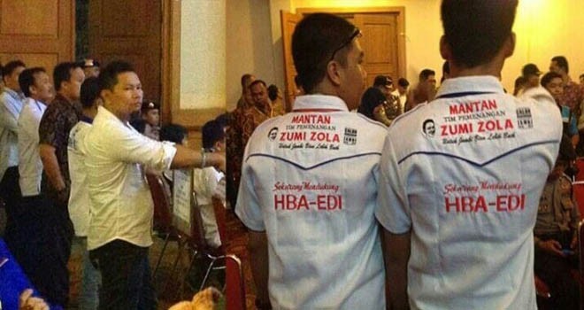 Pemakaian baju betuliskan Mantan Tim Pemenangan Zumi Zola inilah yang dilaporkan oleh tim ZZ-FU ke Bawaslu karena dianggap peleceha terhadap atribut pasangan calon ZZ-FU