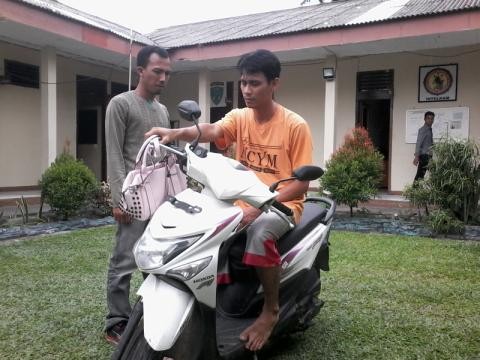 Tersangka Ridho bersama barang bukti sepeda motor dan tas korban