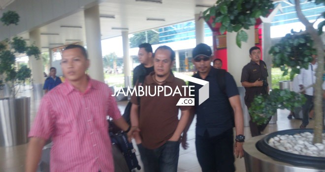 Alven Stony (tengah) digiring petugas dari kejaksaan saat sampai di Bandara Jambi