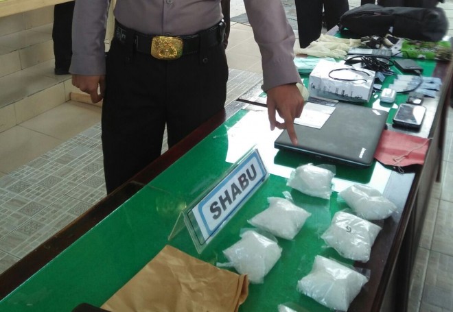 Salah satu anggota polisi menunjukkan barang bukti sabu yang diamankan dari tersangka Roni