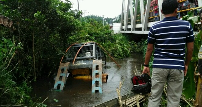 Terlihat mobil teronton terperosok ke sungai.