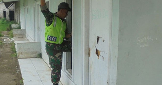 Babinsa Gekbrong, Pelda Dudu Abdulah memeriksa keadaan kosan kosong dan masuk lewat jendela karena sering digunakan mesum dan pesta miras. (Radar Cianjur/JawaPos.com)