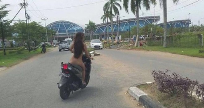 Pengendara mobil mengabadikan Rus alias Dona yang mengendarai sepeda motor tanpa busana di Jalan Ahmad Yani II, Sungai Raya, Kubu Raya, Minggu (15/1). Foto: NETIZEN FOR RAKYAT KALBAR