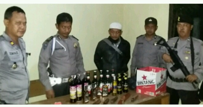 Polisi saat berhasil mengamankan puluhan botol miras dan lima sajam. 