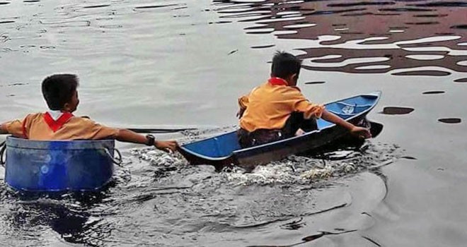 Meski banjir tinggi, dua murid SD di Desa Melintang, Kecamatan Muara Wis, Kukar, tetap berangkat ke sekolah. (Hermansyah/Samarinda Pos)