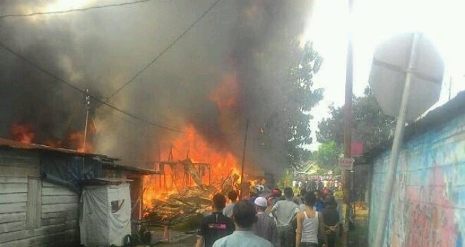 Tampak api membakar rumah warga.