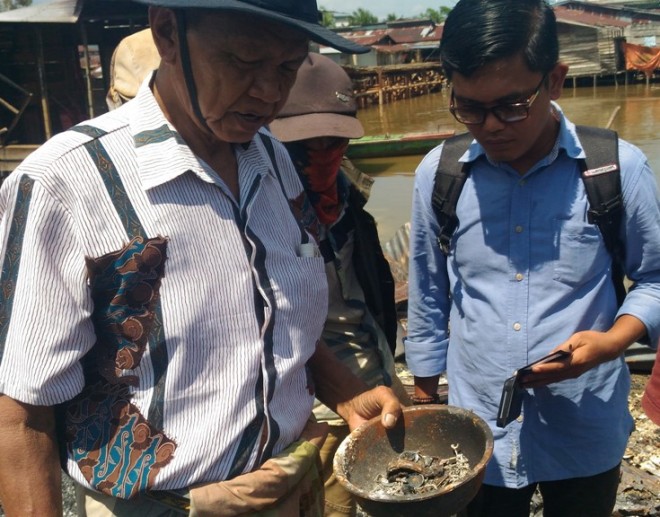 Mansur, pemilik toko emas memperlihatkan emas miliknya yang sudah gosong.