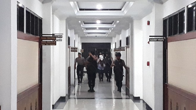 Seorang perempuan masuk ke Polda Jambi dengan menutup wajah. 