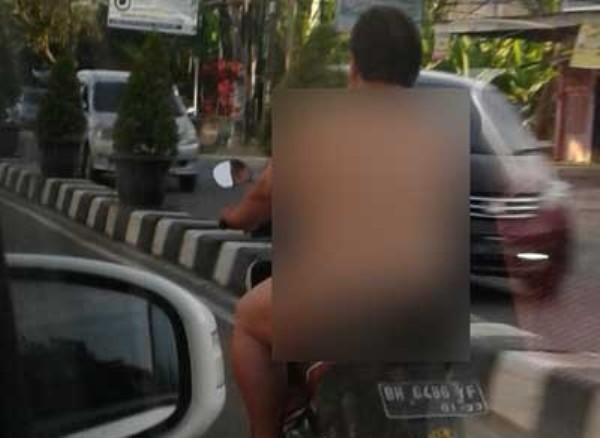 Seorang pria mengendarai motor tanpa busana.