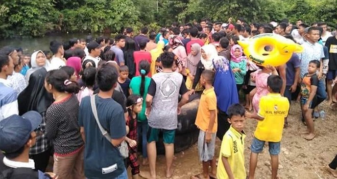 Warga saat mengevakuasi korban Sinta Rahmawati yang tenggelam di Sungai Lubuk Beringin, Kabupaten Bungo, Minggu (24/6).