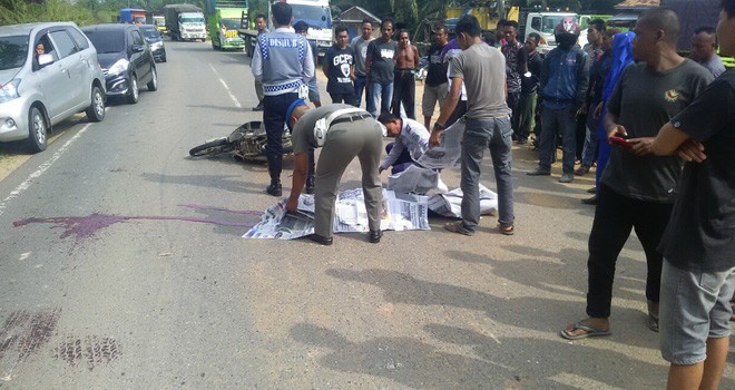 Pihak kepolisian dibantu oleh warga saat mengevakuasi korban di tengah jalan usai terjadinya kecelakaan, Rabu (8/8).