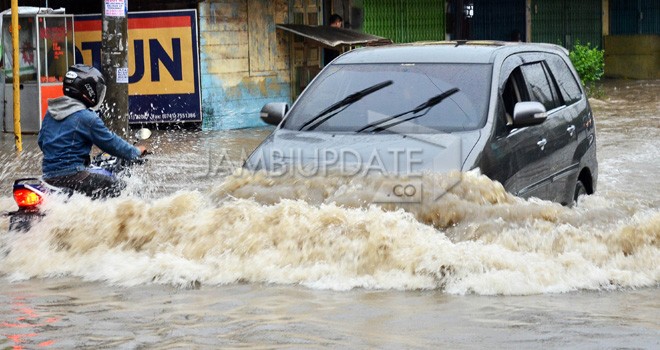 Rumah warga yang teremdan banjir di Kota Jambi, Sementara di bagian lain, kendaraan nekad melintas di tengah banjir