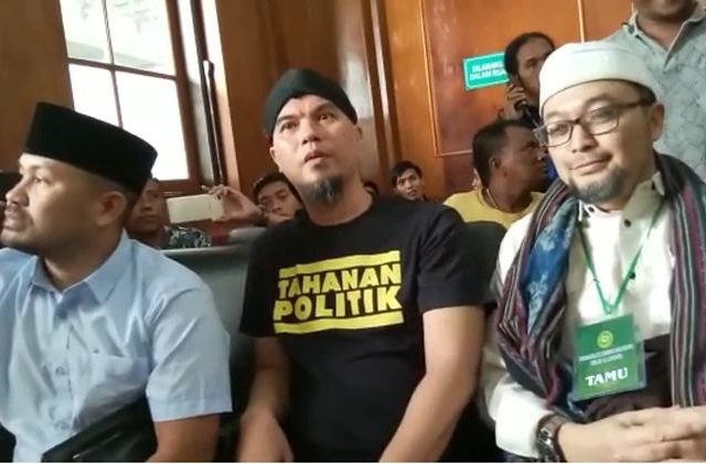 Ahmad Dhani (tengah) mengenakan kaus bertuliskan Tahanan Politik saat disidang di PN Surabaya, Kamis (7/2). (Aryo Mahendro/ JawaPos.com)