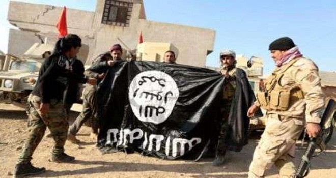 Tentara Iraq berpose didepan bendera ISIS. Foto : AFP