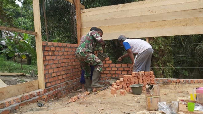 Babinsa Koramil 415-04/MB Sertu Bambang Sutomo membantu warga membangun rumah di RT 06 Desa Ladang Peris. 