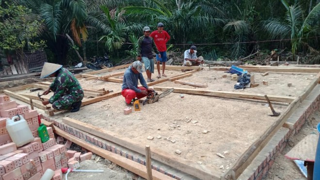 Babinsa Koramil 415-04/Muara Bulian Serda Tri Purwanto membantu warga gotong royong membangun rumah Supar (39) di RT 12 Desa Ladang Peris. 