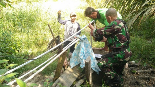 Babinsa Ridhuan dan Kades Ladang Peris serta warga  mengangkat tedmond dan perbaiki instalasi air.