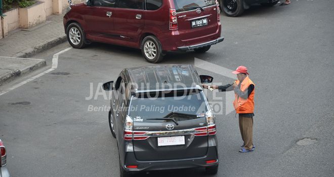 Salah seorang juru parkir di Jalan Sultan Thaha mengatur kendaraan yang keluar dari parkir (2/9).