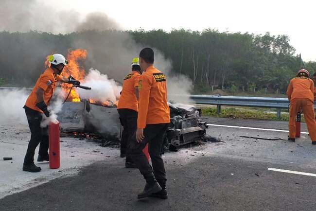 Tim Basarnas Lampung berupaya memadamkan api yang membakar mobil sedan BE 1230 BK dalam kecelakaan di Jalan Tol Trans Sumatera (JTTS) Km 96, Sabtu (19/10).