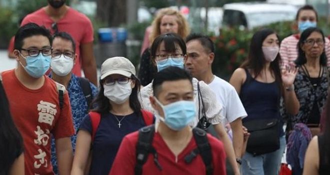 Warga Singapura menggunakan masker untuk mencegah terinfeksi virus corona.