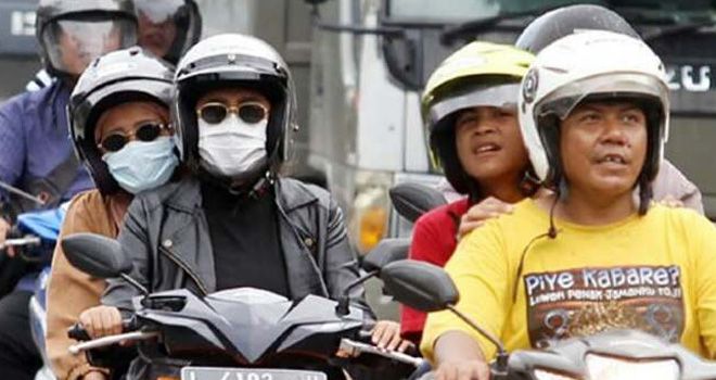 Warga menggunakan masker ketika berkendara di jalan. Sejak wabah korona merebak, harga masker pun melonjak.