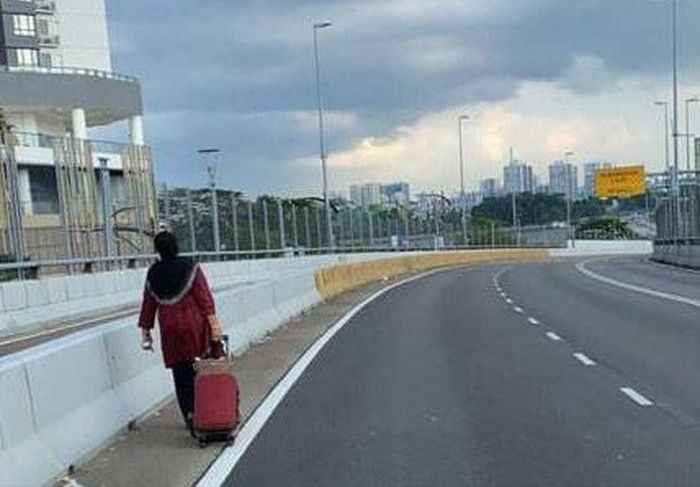 Di Sepanjang jalan yang sepi, wanita ini sesekali beristirahat karena kecapean. 