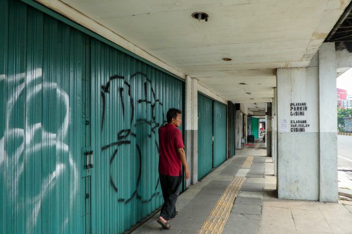 Seorang pria berjalan melewati toko-toko yang tutup di Chinatown menyusul penerapan pembatasan sosial berskala besar di Jakarta sejak Jumat (10/4). 