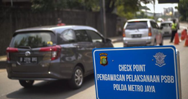 Sejumlah petugas kepolisian bersama Dishub menggelar pengawasan dalam pelaksanaan PSBB hari pertama di Jalan Daan Mogot, Jakarta Barat, (10/4). Para pengguna jalan diawasi petugas untuk diperingatkan memakai masker. Baik kendaraan bermotor maupun mobil warga wajib mengenakan masker. Pengendara yang tidak mengenakan masker diarahkan untuk putar balik kembali ke arah Tangerang. Pengendara mobil juga diwajibkan untuk melakukan social distancing dengan memberi jarak duduk. FOTO: