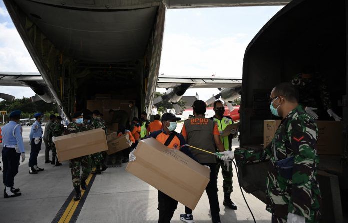 Personel TNI AU menurunkan kotak peralatan pelindung dari pesawat militer untuk dikirim ke staf medis di bandara Internasional Ngurah Rai, Bali pekan lalu.