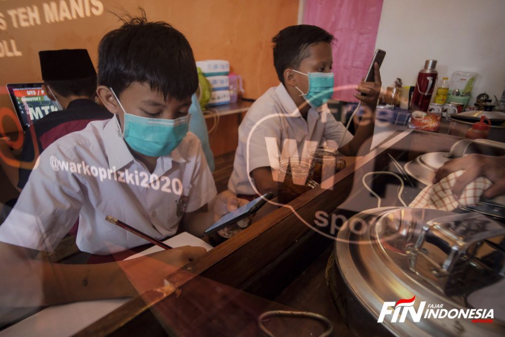 Sejumlah siswa sekolah dasar belajar dengan menggunakan wifi gratis yang di sediakan oleh warkop Rizki, di Pondok Aren, Tangerang Selatan, Rabu (29/7). 