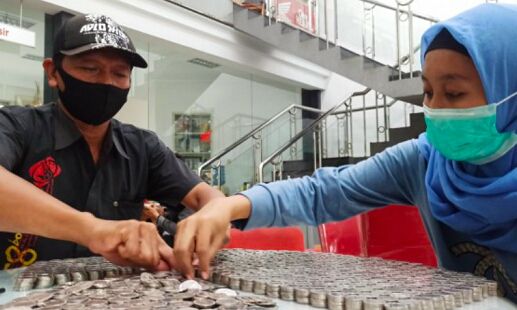 Amidah (kanan) dibantu konsumen lain sedang menghitung uang koin untuk mbeli sepeda motor baru.