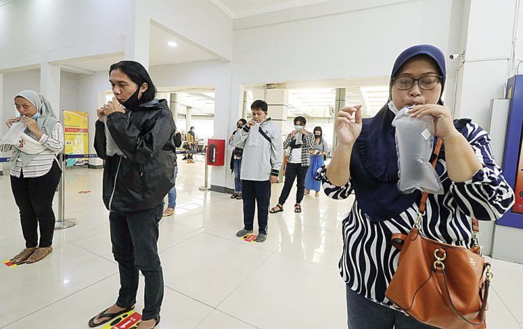 Calon penumpang KA mengembuskan napas pada kantong plastik untuk tes GeNose di Stasiun Pasar Senen, Jakarta, kemarin (3/2).