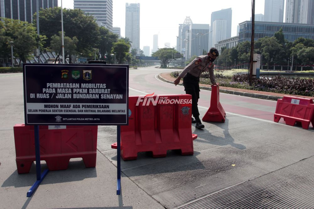Anggota Kepolisi memberhentikan pengendara yang ingin melintas jalan Sudirman saat berlangsungnya Pemberlakuan Pembatasan Kegiatan Masyarakat (PPKM) Darurat di kawasan Bundaran Senayan, Jakarta, Sabtu (3/7).