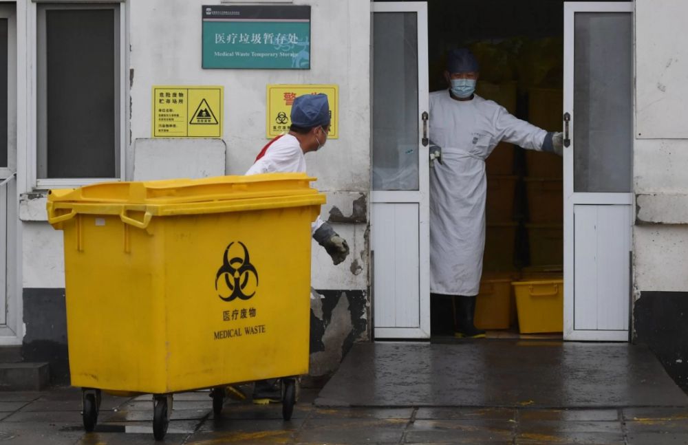 Seorang pekerja membawa gerobak penuh dengan limbah medis melewati kamar mayat, ke fasilitas penyimpanan di Rumah Sakit Youan di Beijing, kemarin. 