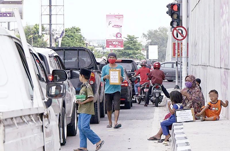 Pengemis anak-anak maupun orang tua beroperasi di jalan protokol. 