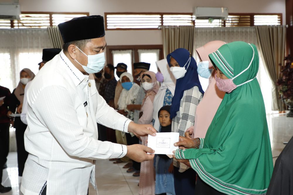 PENYERAHAN: Bupati Bungo H. Mashuri menyerahkan zakat konsumtif yang dikelola oleh Baznas Bungo untuk 13.967 penerima se kabupaten Bungo