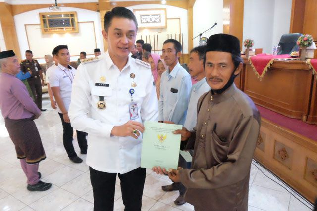 Bupati Muaro Jambi Bachyuni Deliansyah saat menyerahkan sertifikat hak atas tanah kepada pelaku UMKM dan pembudidaya ikan.