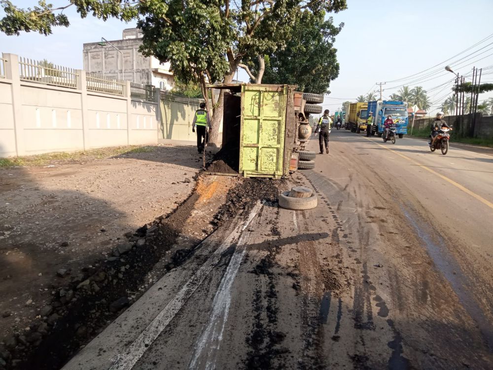 Pemandangan truk batu bara terguling di jalan raya Jambi. 