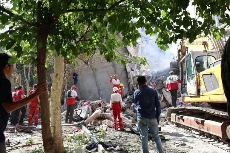 Petugas penyelamat bekerja di lokasi bangunan yang rusak akibat serangan udara Israel, di Teheran, Iran, Jumat (13/6/2025).